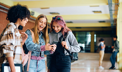 group of high school students looking at a phone