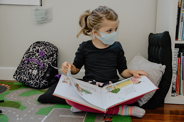Girl wearing a mask and reading a book