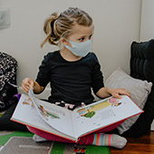 Girl wearing a mask and reading a book