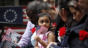 girl waves flag at naturalization ceremony