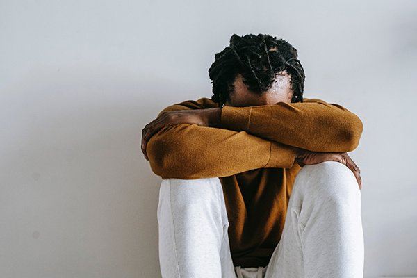 Man rests his face on his knees