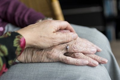 older adult holding hands with younger adult