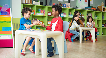 two pre-k students in classroom play at a table