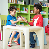 two pre-k students in classroom play at a table
