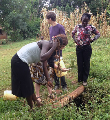 A researcher working with two local women to retrieve water from the ground